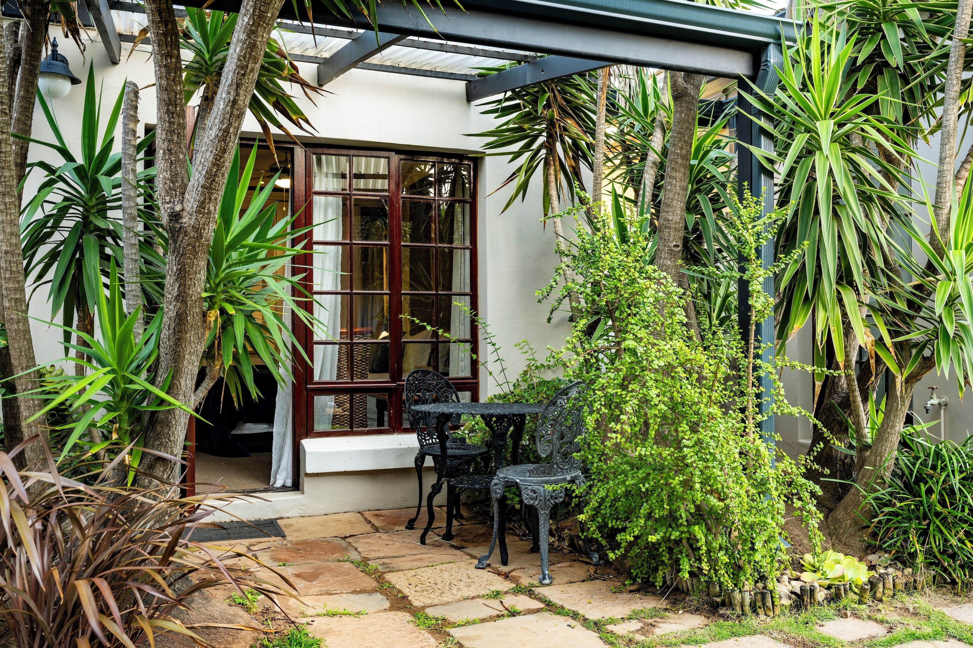 A patio with stone flooring, two black metal chairs, and a table.