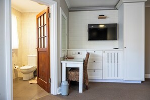 A bathroom with a toilet, a shower, a sink, and a mirror.