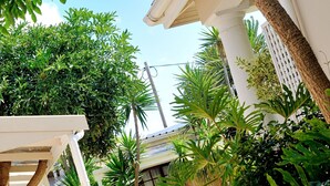 Une cour avec un grand pot, des plantes en pot et une pergola blanche.