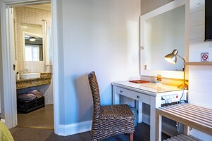 Habitación de hotel con baño, escritorio con lámpara y una silla.