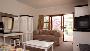 Una sala de estar con sofá, mesa de centro, televisor, escritorio y ventana con vistas al exterior.