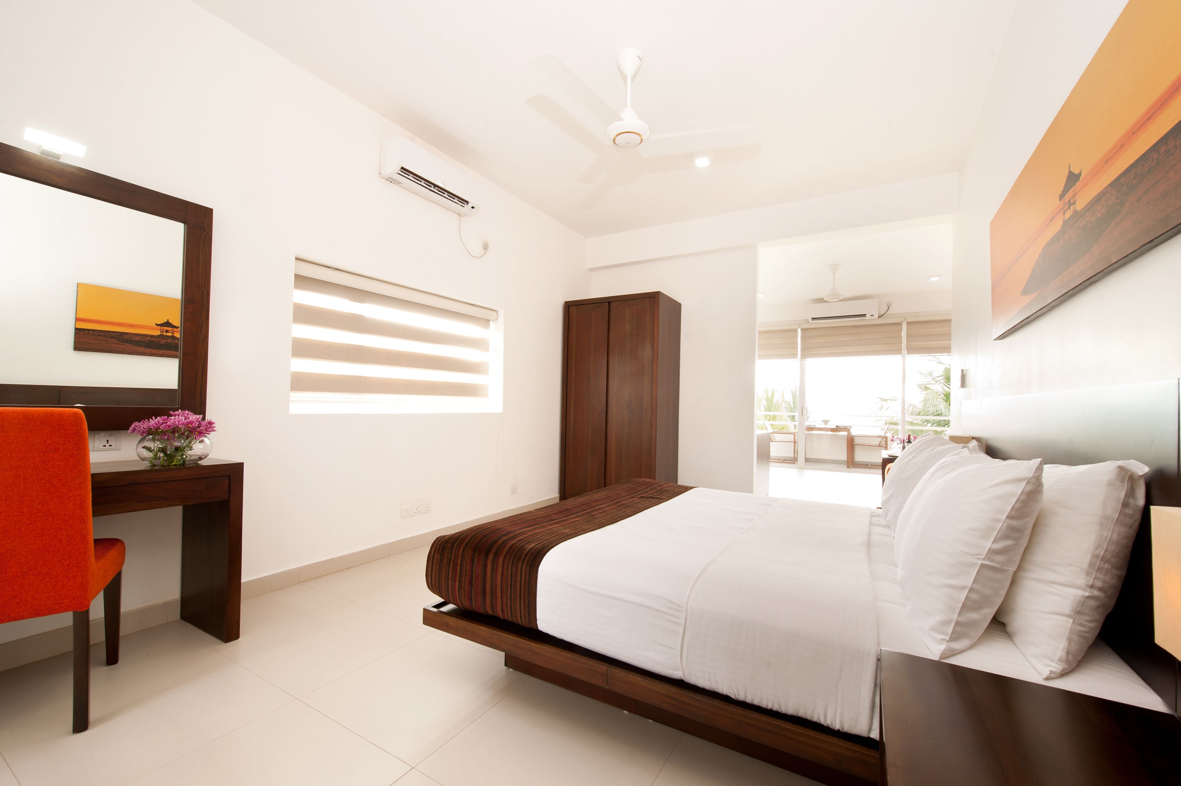 A modern bedroom with a bed, a desk, a chair, and a wardrobe.