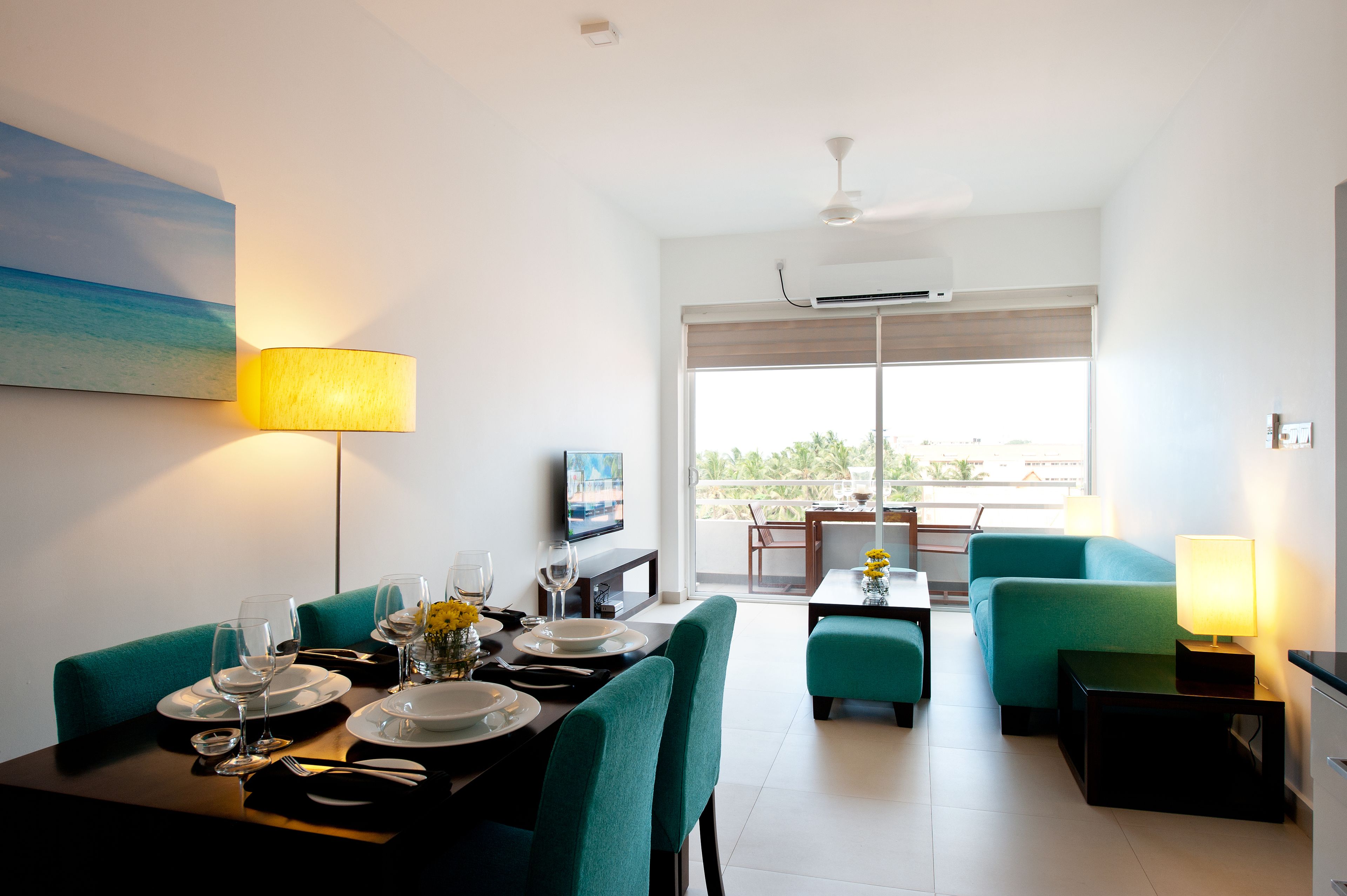 A modern dining area with a table set for two, a sofa, and a TV in the background.