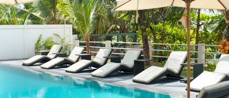 A pool area with lounge chairs and umbrellas.