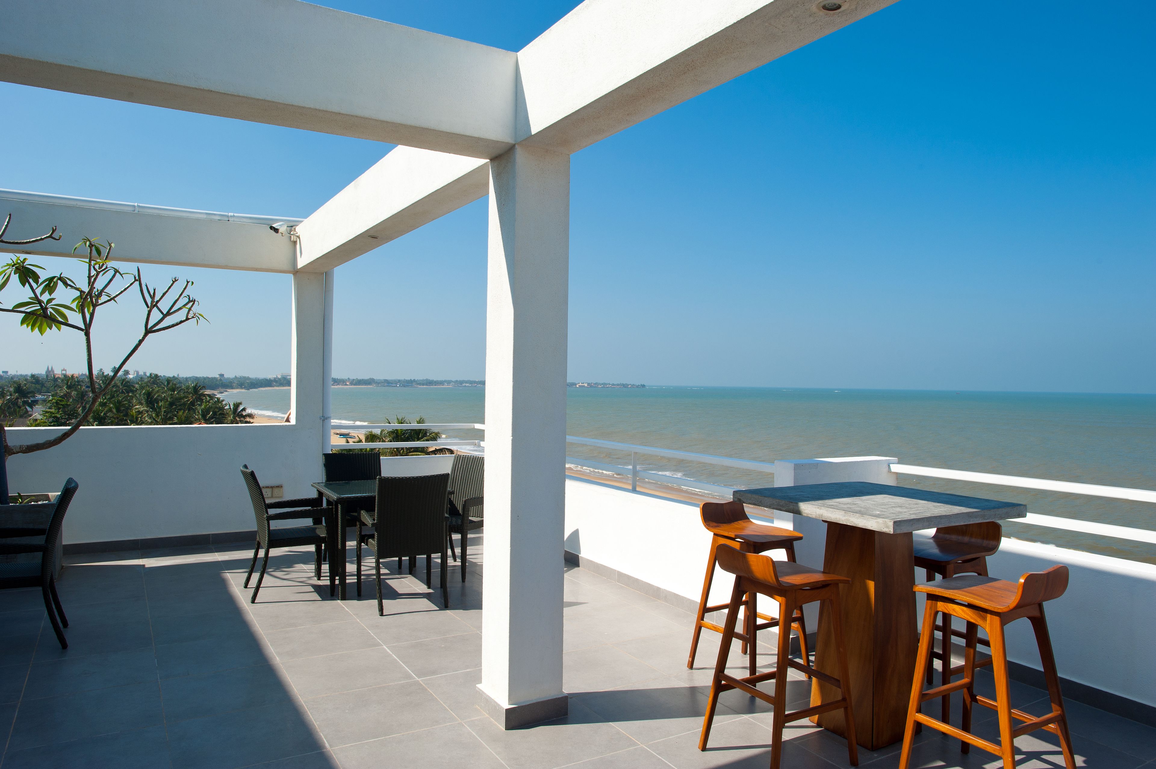 Una terraza con vista al mar, que incluye una mesa, sillas y una planta en maceta.