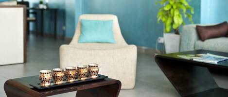 A modern living room with a sofa, a coffee table, and a side table with decorative candles.