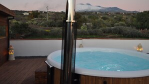 Un bain à remous sur une terrasse en bois, avec une vue sur les montagnes en arrière-plan.