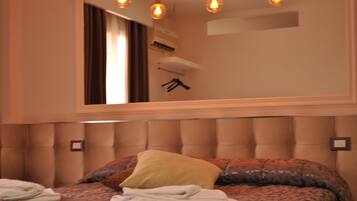 A bedroom with a tufted headboard, a large mirror, and a bed with patterned bedding and pillows.