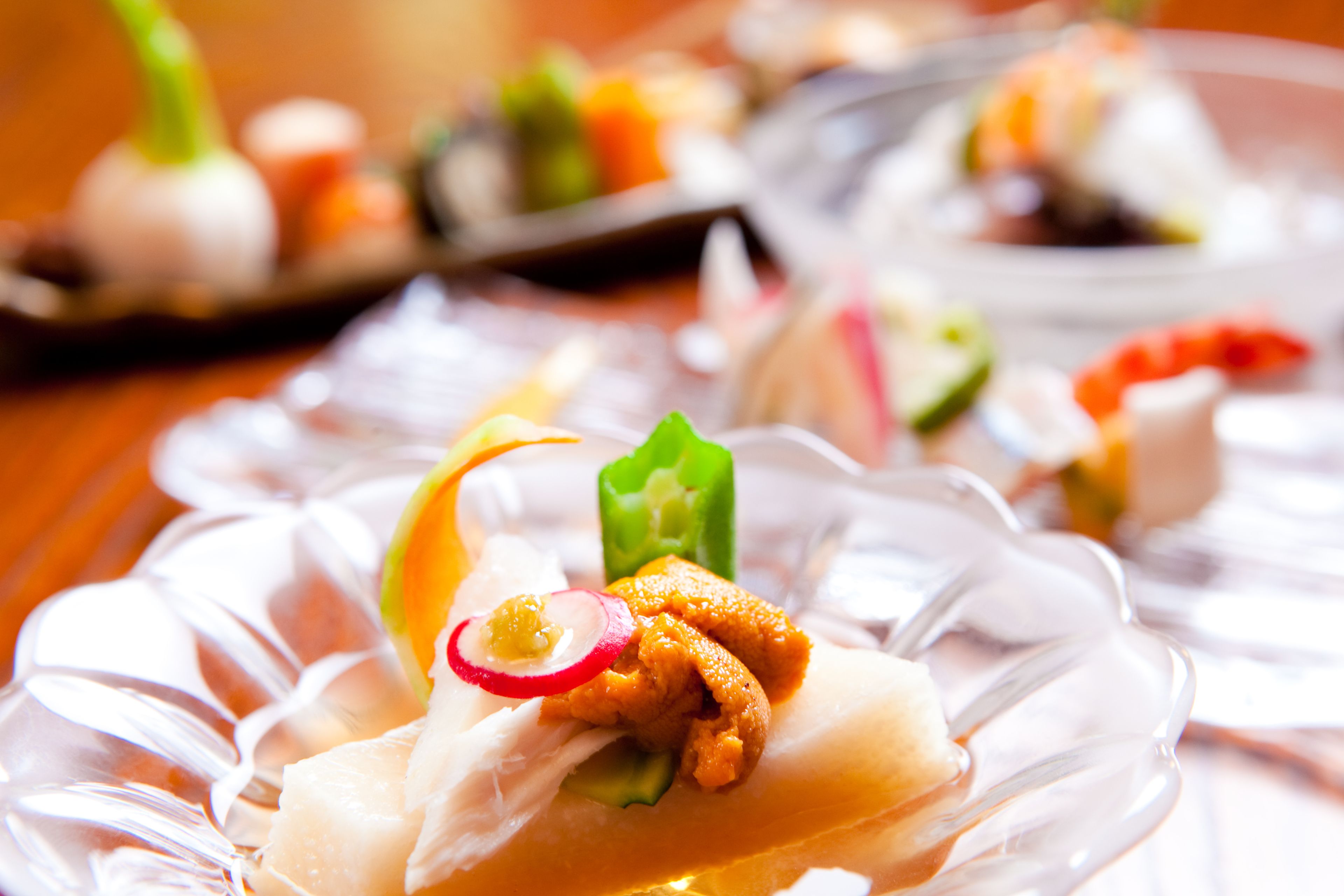 A close-up of a glass plate with a food item garnished with radish and green pepper.