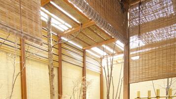 Uma onsen japonesa tradicional com banheira de pedra, estruturas de bambu e uma mesa de madeira.
