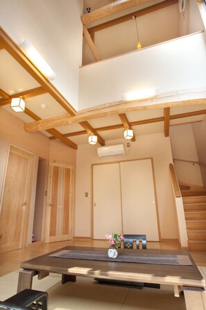 Ein modernes Interieur mit Holzboden, einem Esstisch mit Blumenvase und einer Treppe.