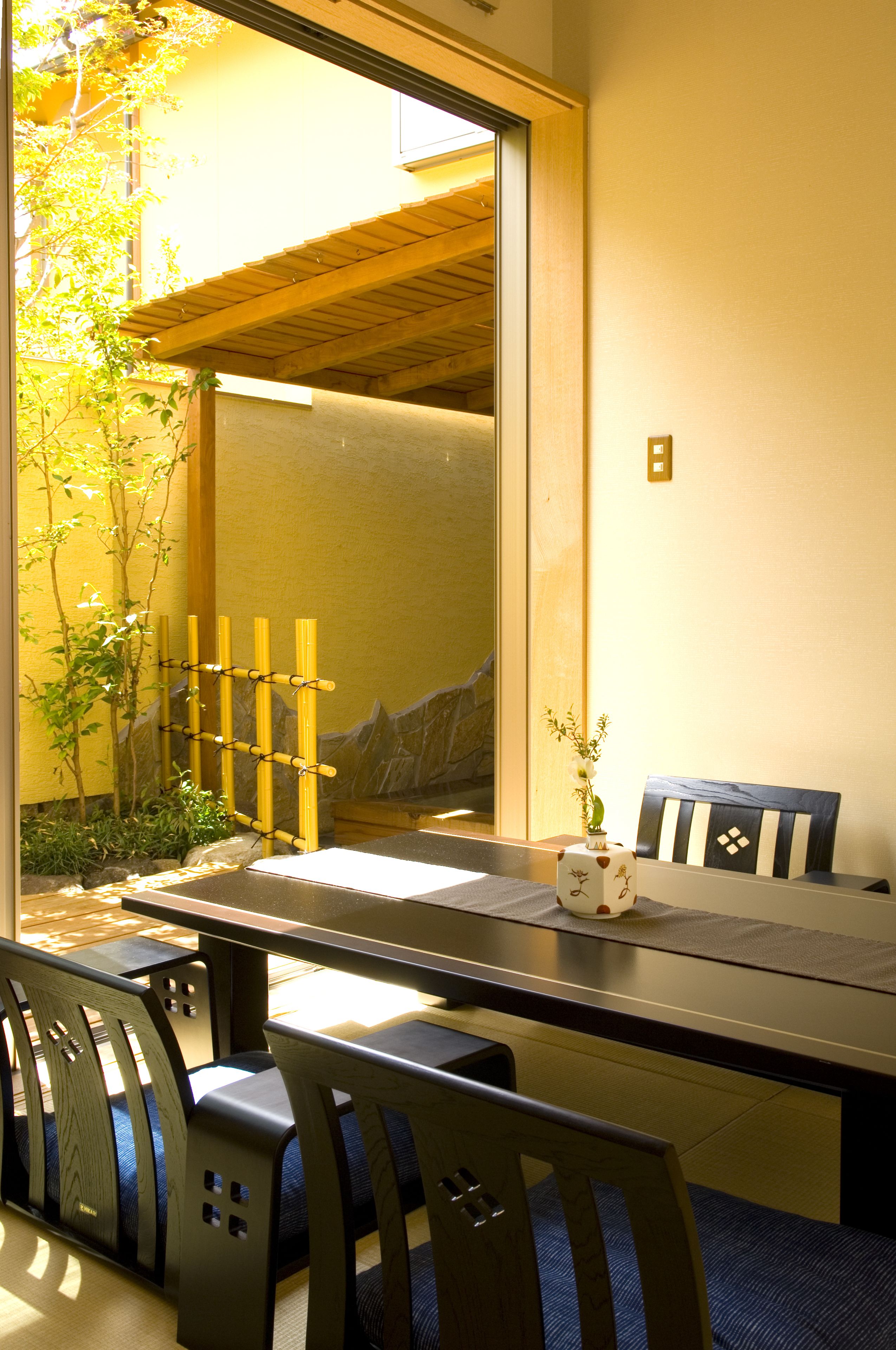 A dining area with a long table, chairs, and a vase of flowers.