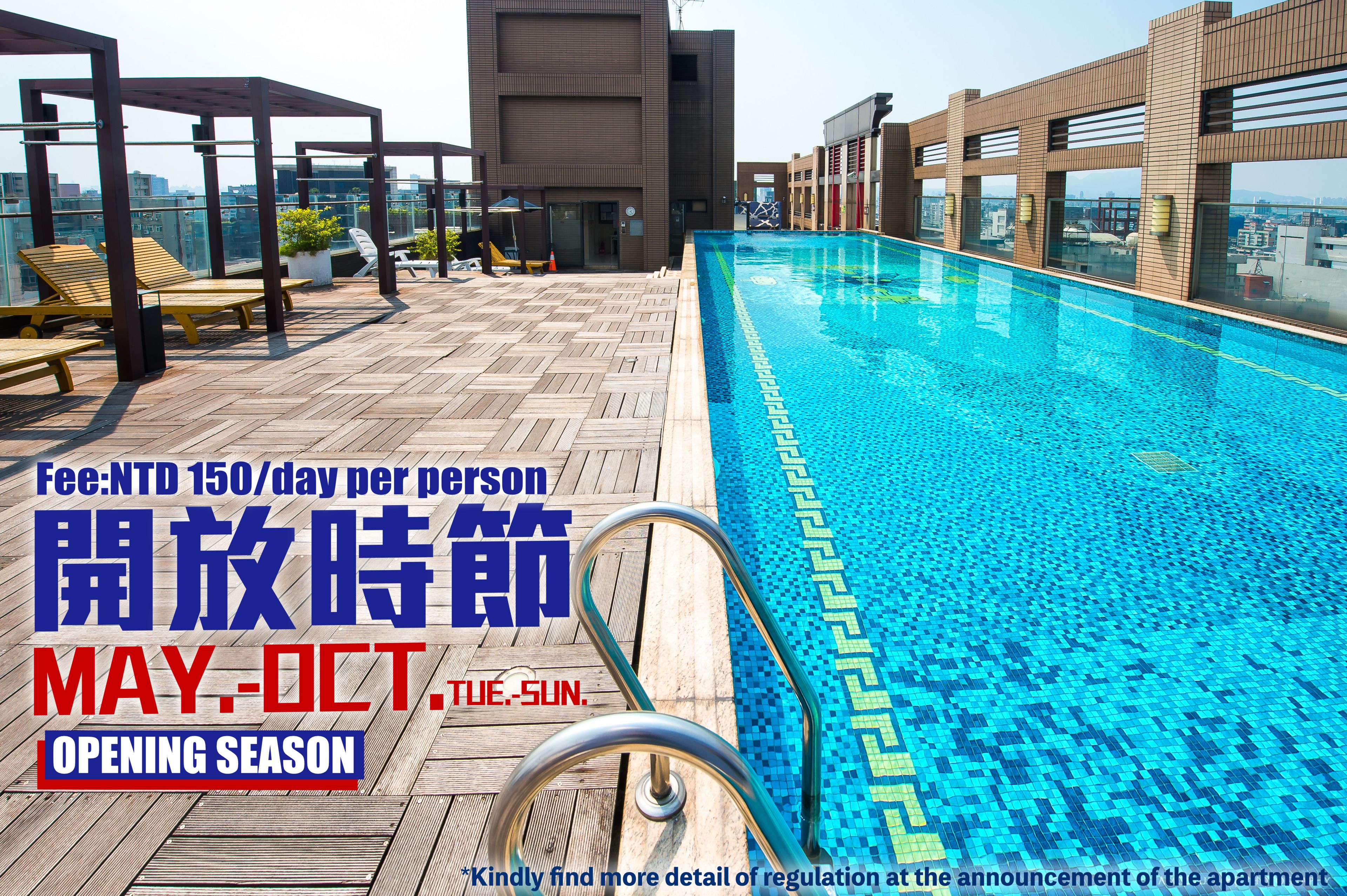 A rooftop pool area with wooden deck, lounge chairs, and a clear blue pool.