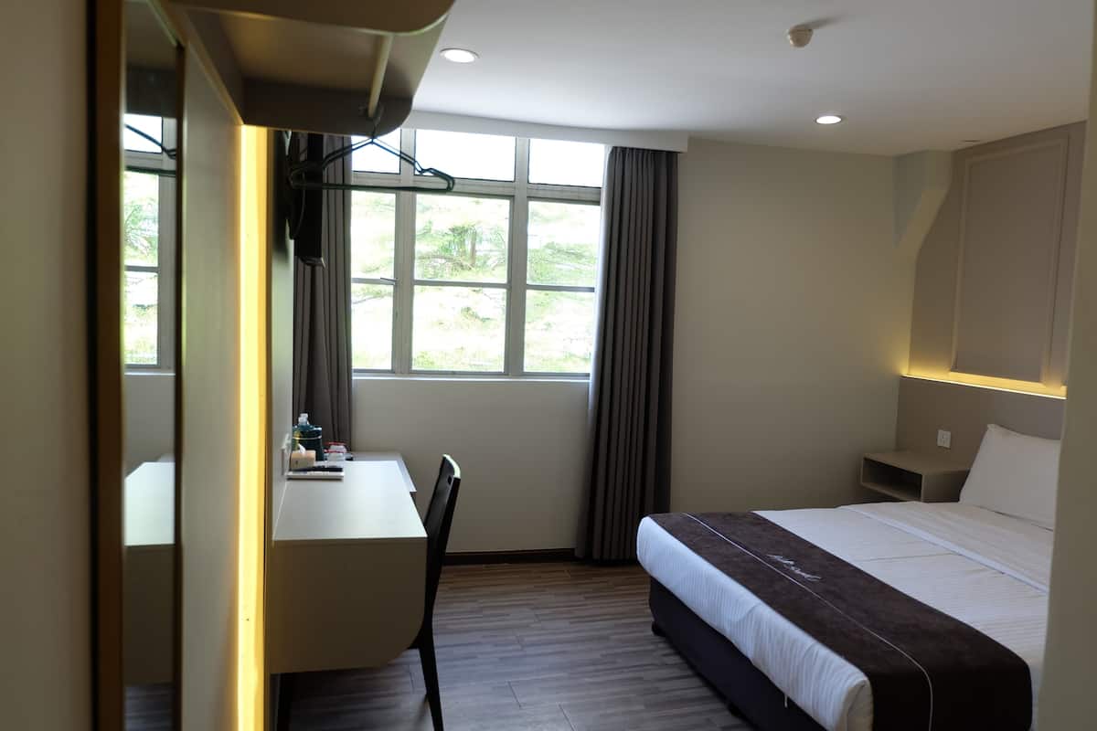 Une chambre d’hôtel avec un lit, un bureau et une chaise.