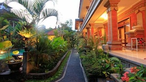 A pathway flanked by lush greenery and a building with classical architecture. - Tanah Semujan Ubud (Ubud)