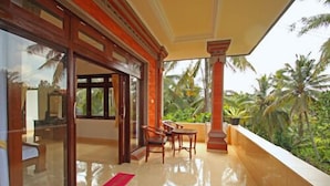 A balcony with a view of palm trees, a glass door, and a red mat on the floor. - Tanah Semujan Ubud (Ubud)