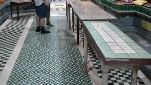 Een tempelinterieur met een man die staat, een groot Boeddhabeeld en een muurschildering.