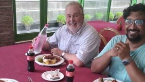 Een eettafel met borden eten, frisdrankflessen en een waterfles.