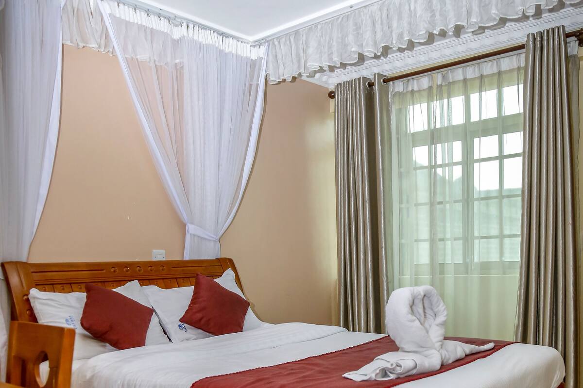 Una cama bien hecha con ropa de cama blanca y roja, un cabecero de madera y una manta roja.