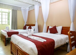 A hotel room with two beds, each with white linens and red bedspreads. There are white curtains and a wooden headboard. - Decasa Hotel (Nairobi)
