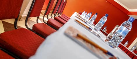 A conference room with red chairs, a white table, and water bottles.