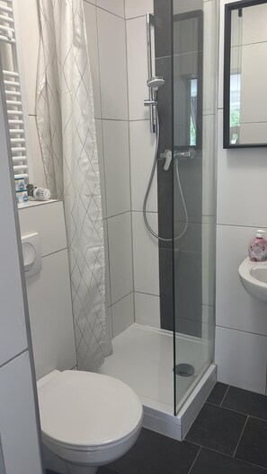 Een douche, handdoeken, zeep, toiletpapier