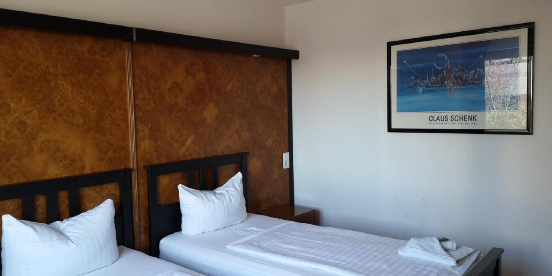 Una habitación de hotel con dos camas, un cabecero de madera y una obra de arte enmarcada en la pared.