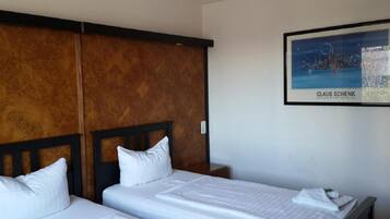 Una habitación de hotel con dos camas, un cabecero de madera y una obra de arte enmarcada en la pared.