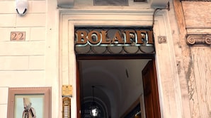 Une entrée d’immeuble avec une enseigne métallique portant l’inscription « BOLAFI » et une porte donnant sur un couloir.