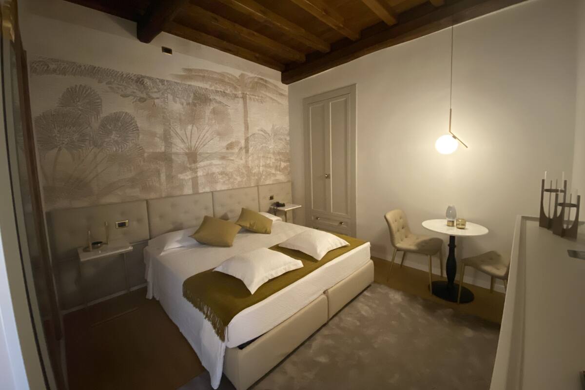 A bedroom with a large bed, a bedside table, a chair, and a small table with a lamp.