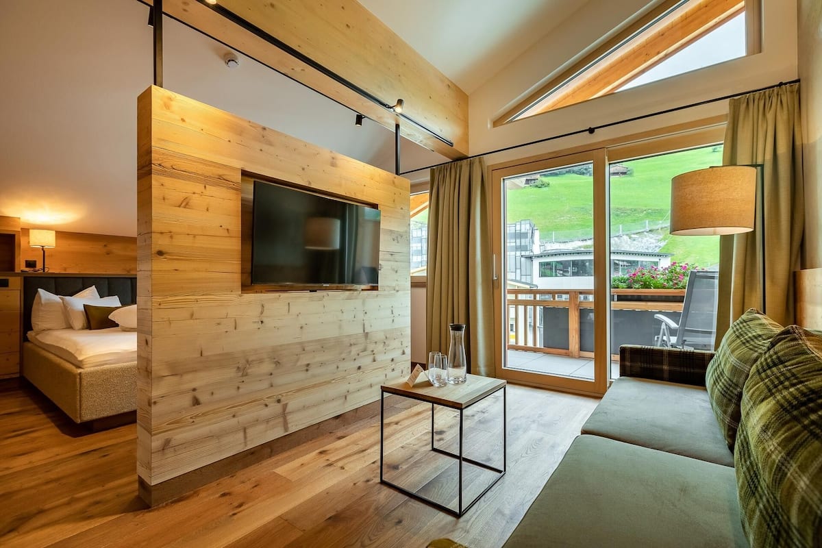 Une chambre moderne avec un mur en bois, un téléviseur à écran plat, une table en verre et un canapé offrant une vue sur l’extérieur.