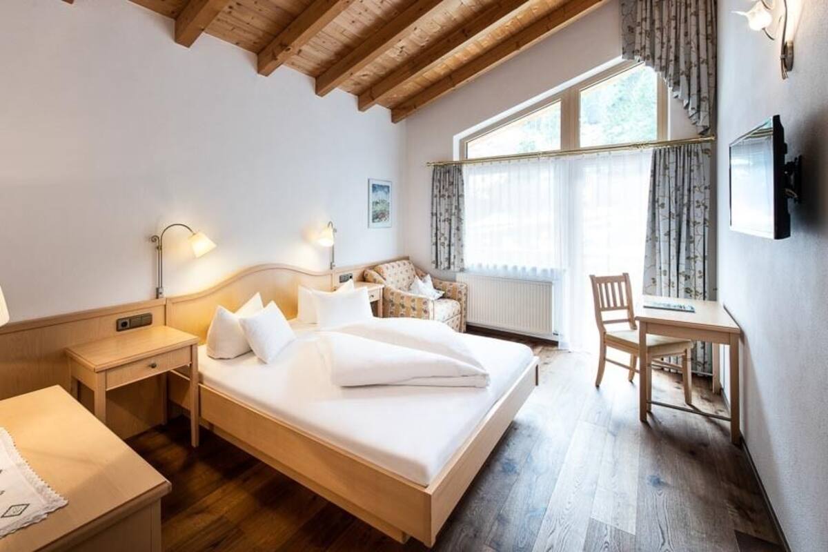 Une chambre d’hôtel avec un lit en bois, des tables de chevet, un bureau et une chaise.