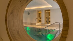Un intérieur moderne avec une structure circulaire en bois, une piscine à fond de verre et un escalier menant à un deuxième étage.
