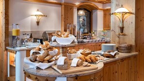 Un comptoir de buffet proposant une variété de pains et de viennoiseries, un espace dédié au café et une lampe murale décorative.