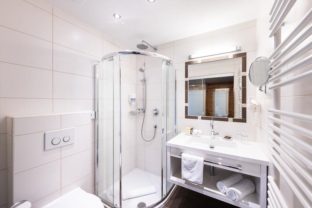 A modern bathroom with a glass-enclosed shower, a white sink, and a mirror above it.
