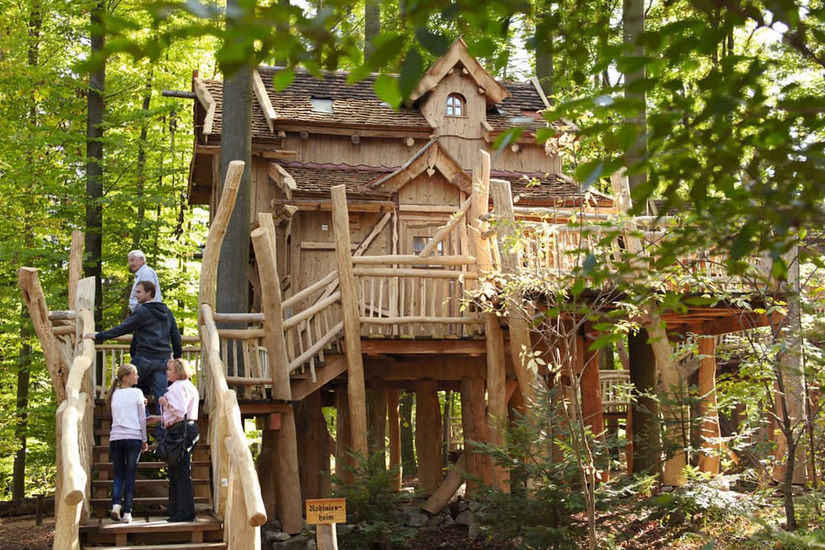 A wooden cabin with a balcony, surrounded by trees.