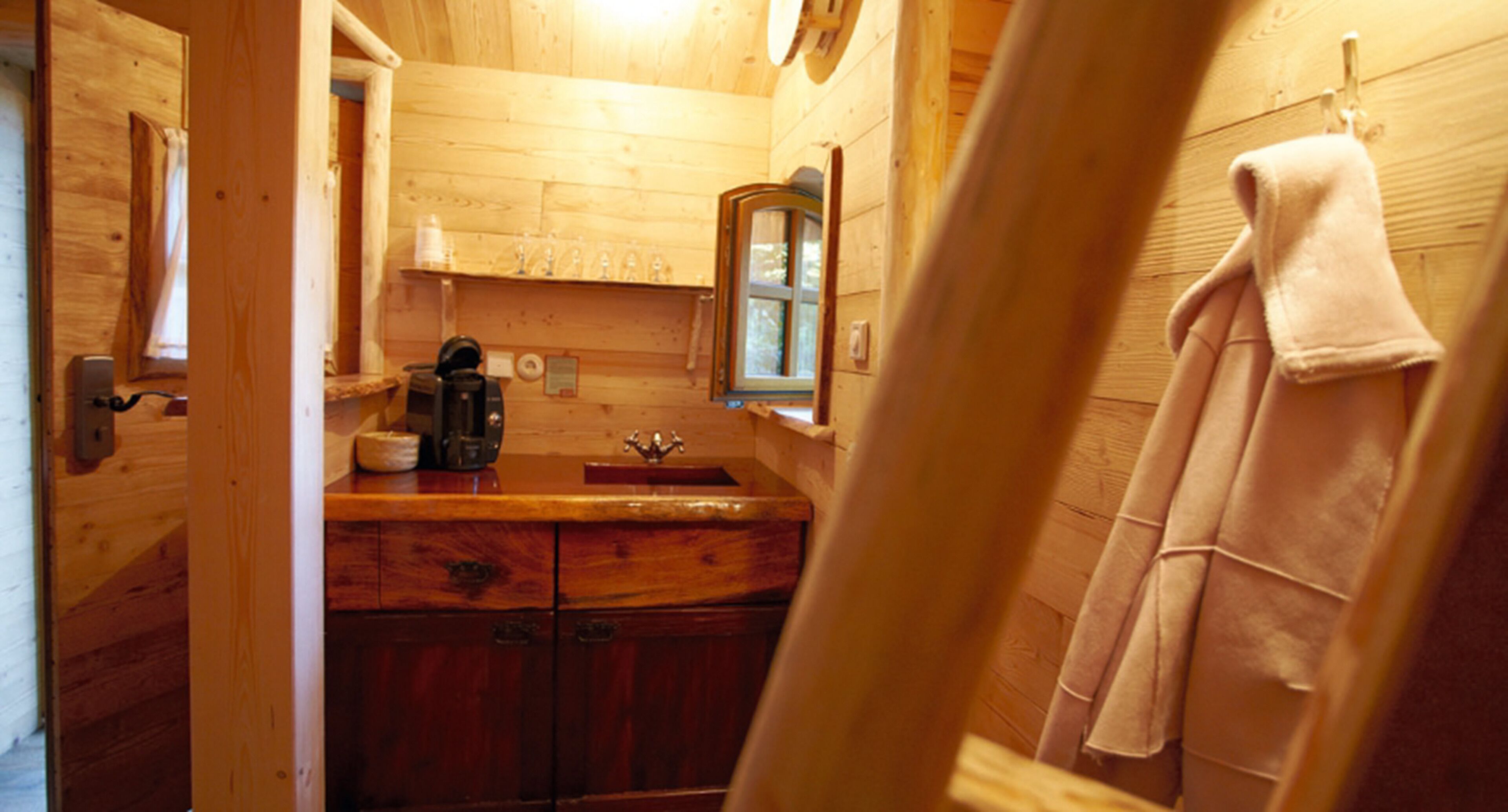 Un bagno in una baita di legno, con un lavabo in legno, uno specchio e un asciugamano appeso al muro.