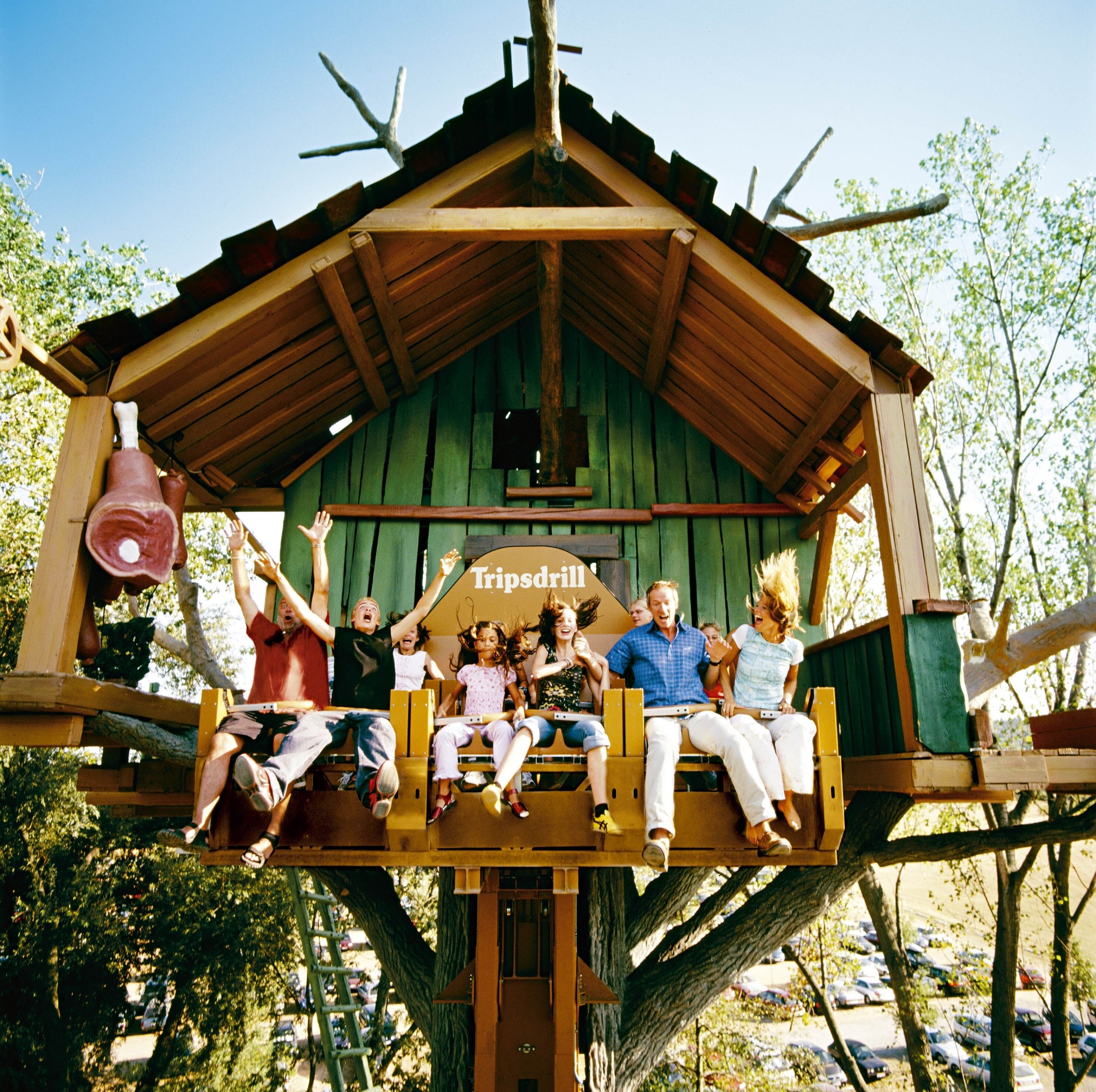A wooden structure with a sign reading "Tripsdell" and people sitting on it.