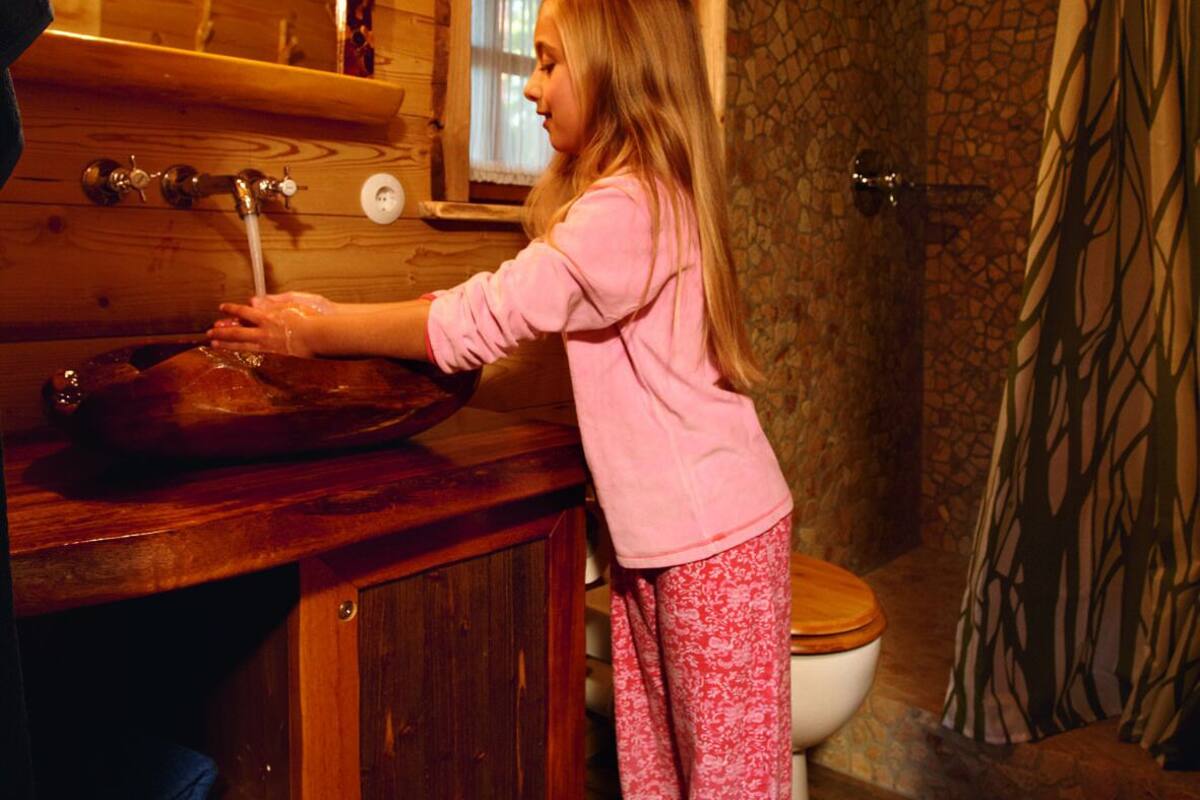 A wooden cabin interior with a rustic bathroom, including a wooden sink and a stone shower area.
