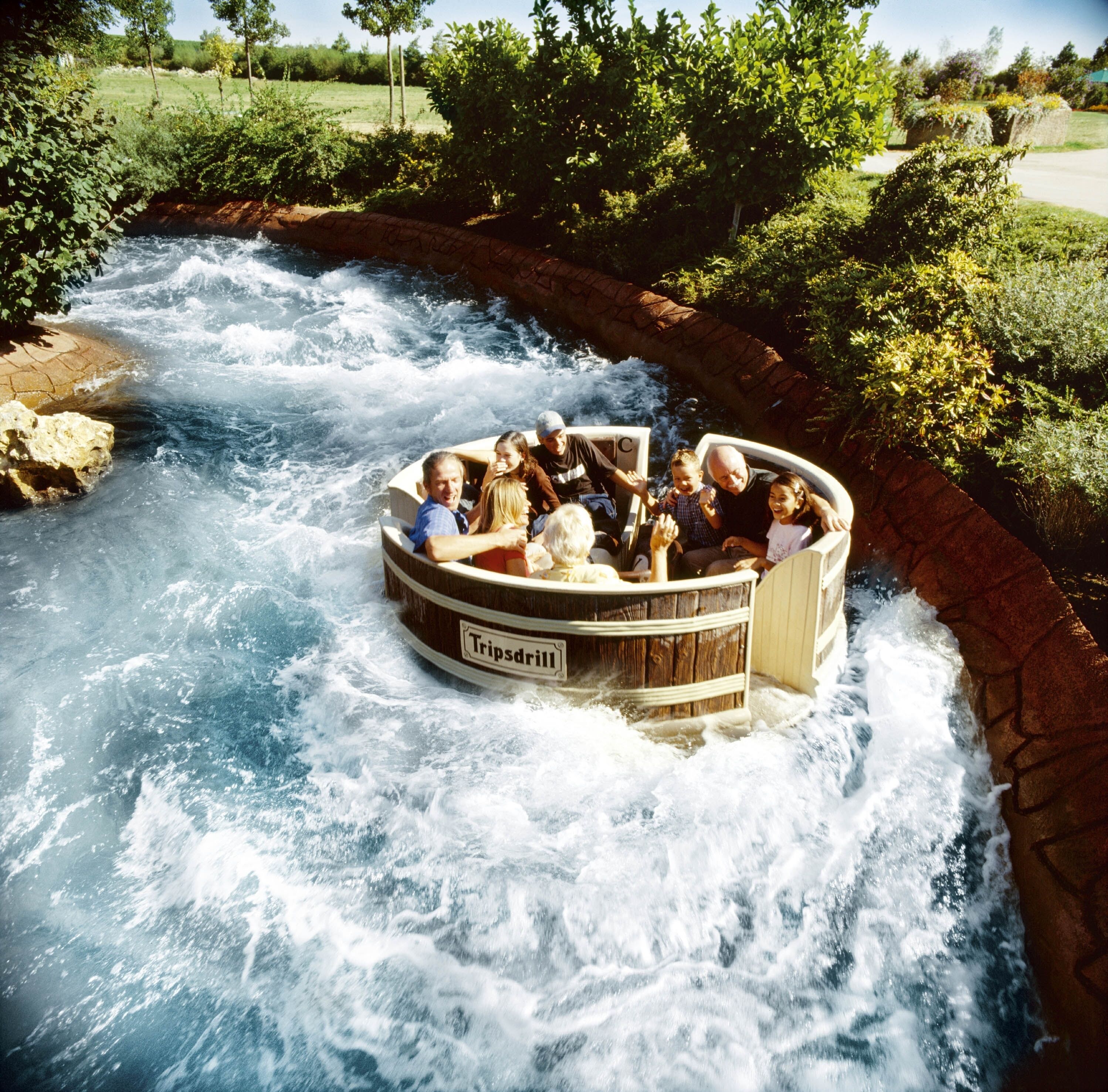 A wooden boat ride with people enjoying the rapids of a river.