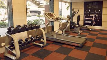 A gym with treadmills, dumbbells, and a poster on the wall.