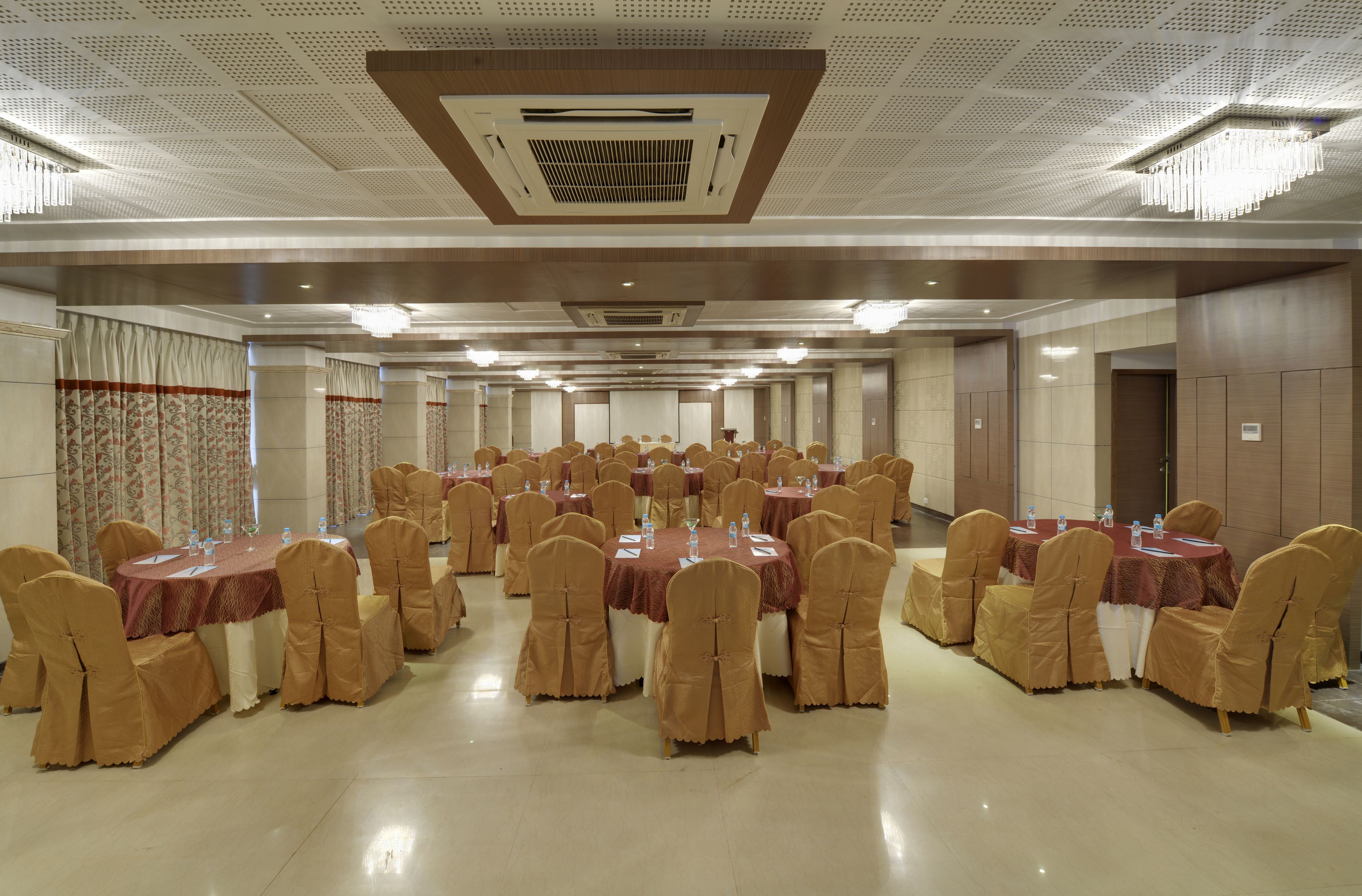 A banquet hall with multiple round tables, each set with chairs and tablecloths.