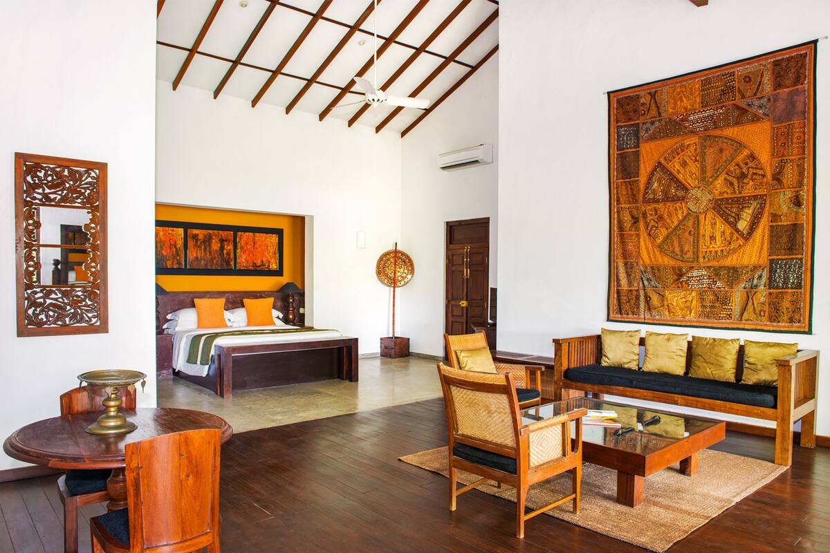 Una habitación amplia con una cama grande, un sofá, una mesa de comedor y una obra de arte de gran tamaño en la pared.