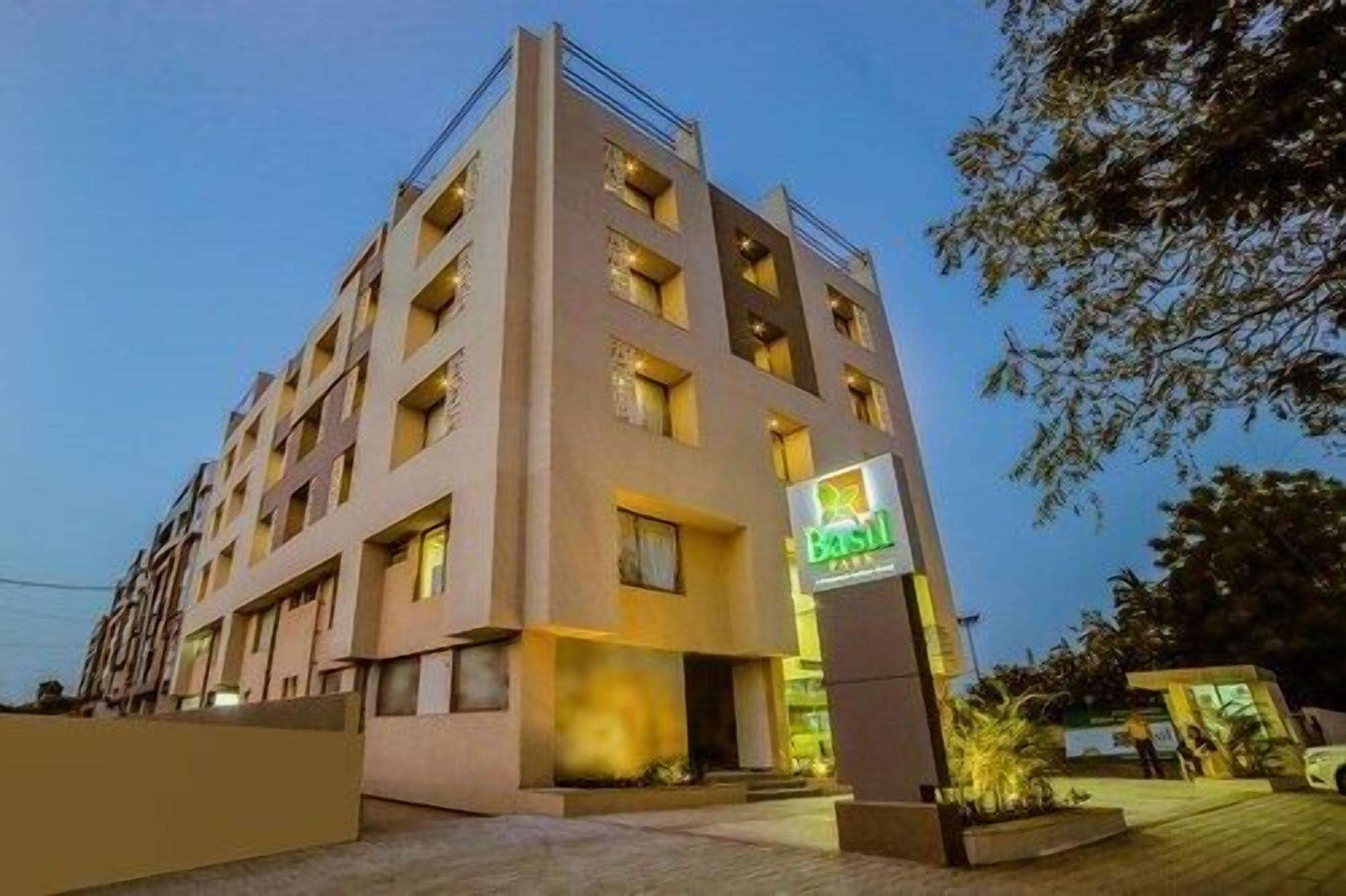 A multi-story hotel with a prominent 'Basil' sign, featuring a modern architectural design with a flat roof and a series of balconies.