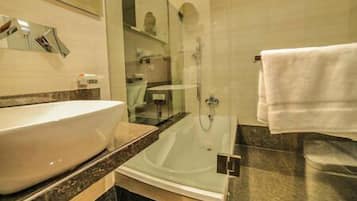 Un baño moderno con un lavabo grande de color blanco, ducha con cerramiento de vidrio y encimera de mármol.