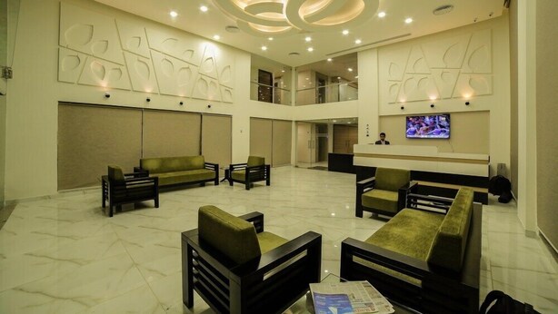 A spacious lobby with a high ceiling, recessed lighting, and a flat-screen TV mounted on the wall.