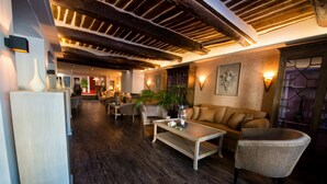 A spacious lobby with a wooden ceiling, a sofa, a coffee table, and a refrigerator. - Nouvel Hôtel du Commerce (Castellane)