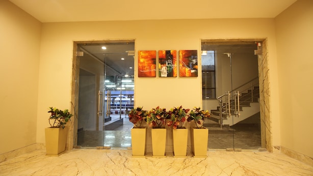 Un vestíbulo con suelo de mármol, un mostrador de recepción con plantas y una escalera.