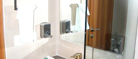 Un baño con un lavamanos blanco, un espejo y una puerta de madera.