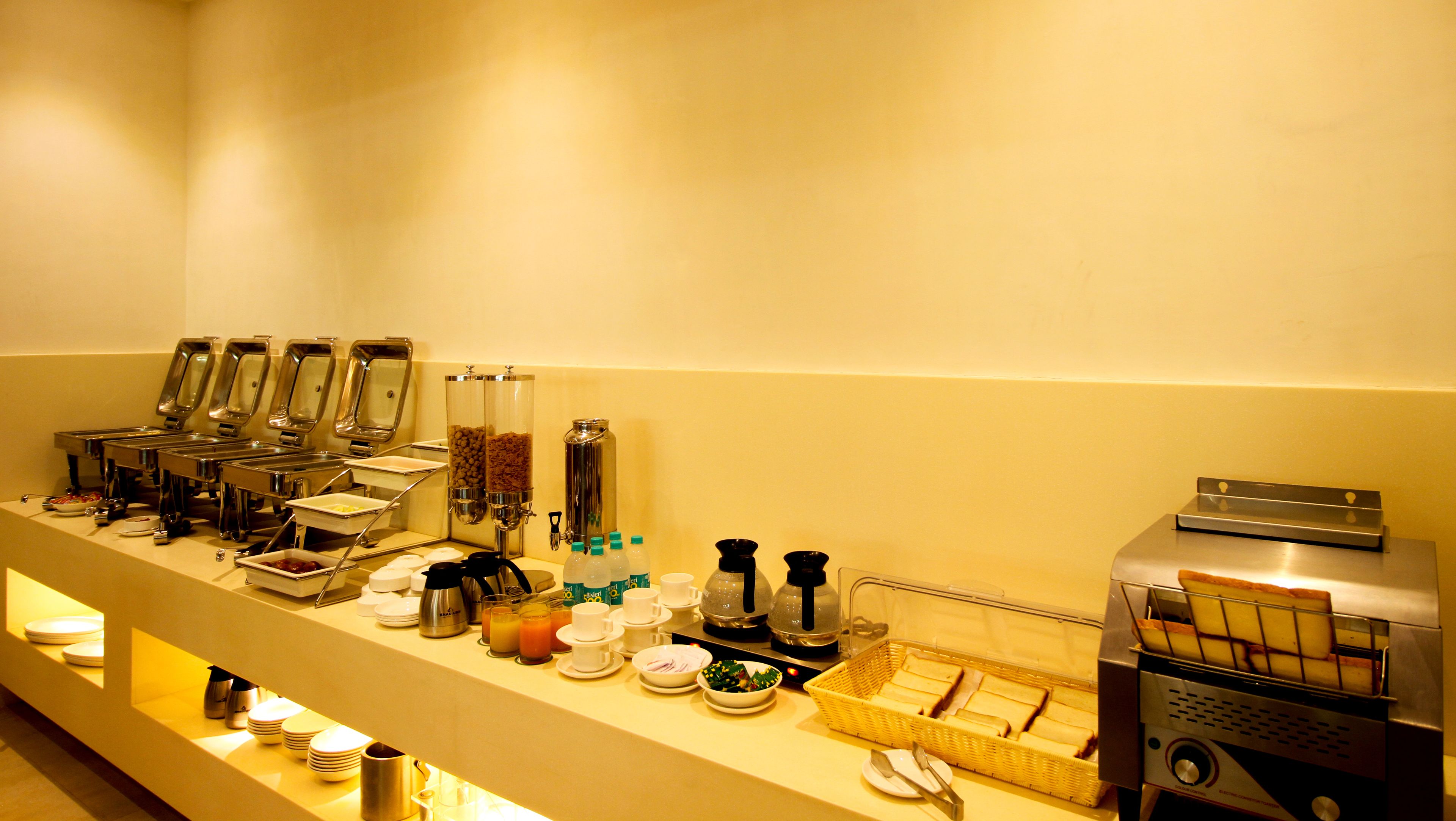 Montaje de bufé con varios dispensadores de comida y bebida, incluyendo una máquina de café y un tostador.